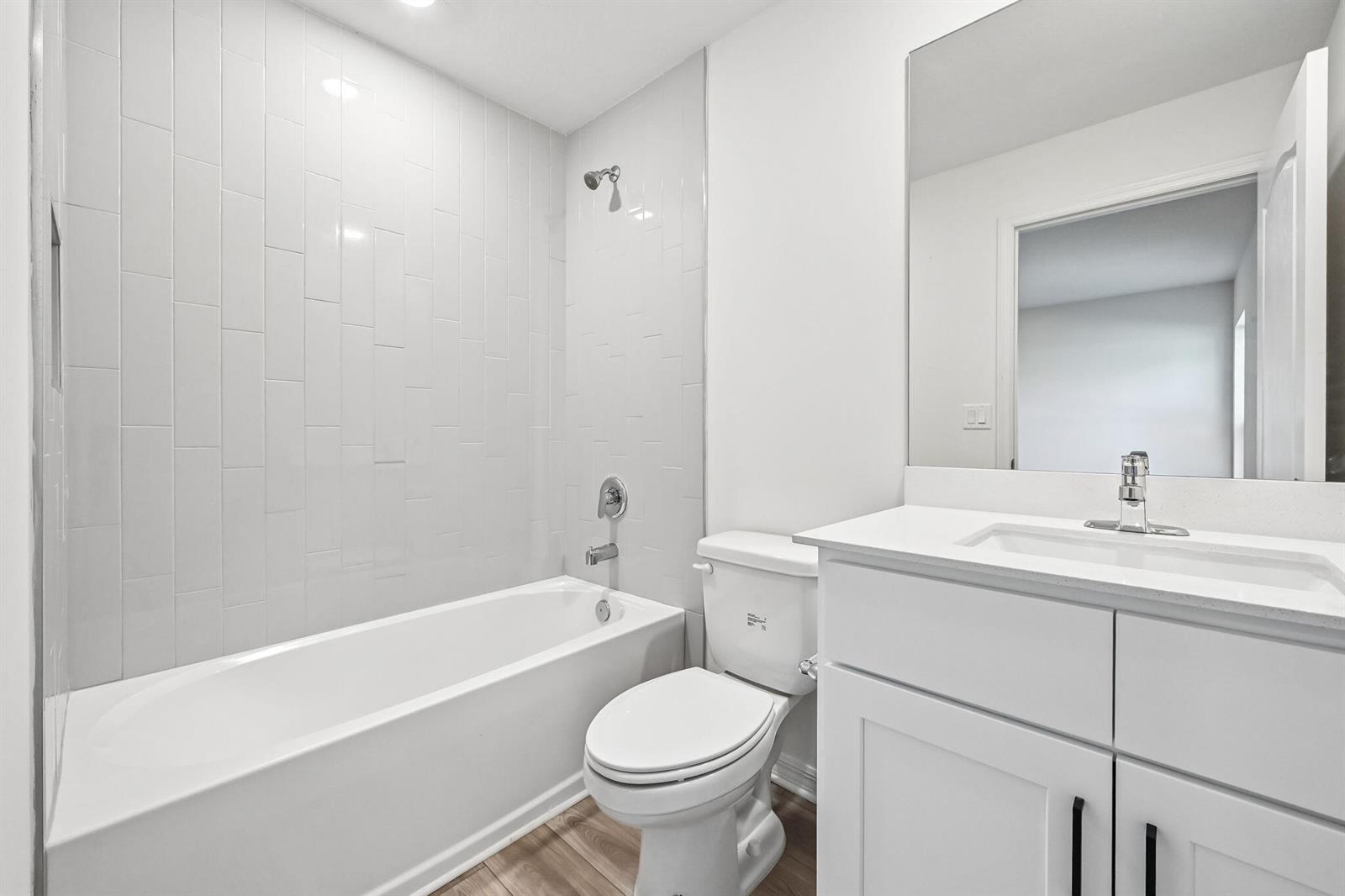 A bathroom features a white vanity, a toilet, and a bathtub with white subway tile — 5717 Palm Drive, Fort Pierce FL 34982, FORT PIERCE, FL