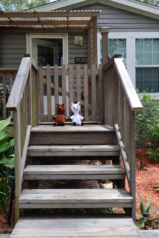 A wooden staircase leads to a front porch with a gate and two plush toys — 9028 WEST STREET, BROOKSVILLE, FL