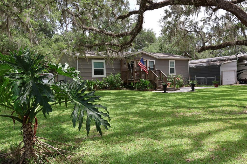 A single-story house with gray siding and a wooden porch sits on a grassy lot — 9028 WEST STREET, BROOKSVILLE, FL