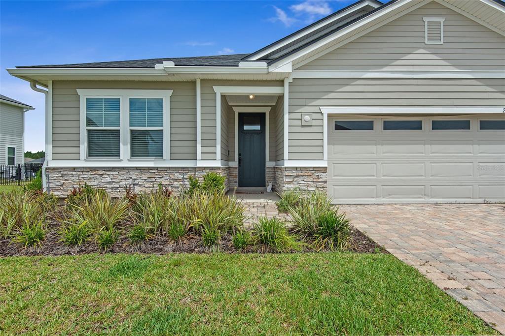 The exterior of a single-story house features light-colored siding, stone veneer, and a paved driveway — 26 WINGED ELM, ST AUGUSTINE, FL