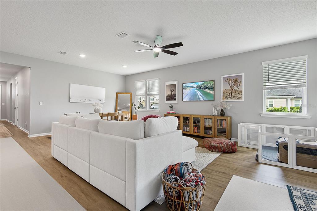 A living room features a white sectional sofa, a wooden media console, and a ceiling fan — 26 WINGED ELM, ST AUGUSTINE, FL