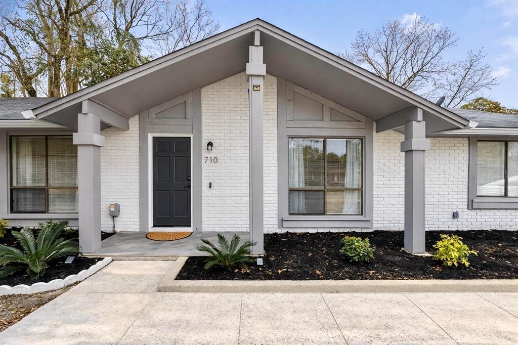 The exterior of a single-story house features white brick walls, gray trim, and a gabled roof — 710 BRIARWOOD DRIVE, WINTER SPRINGS, FL