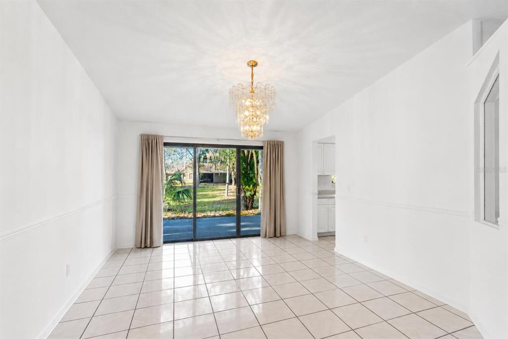 A dining room with white walls, tile flooring, a crystal chandelier, and sliding glass doors — 710 BRIARWOOD DRIVE, WINTER SPRINGS, FL