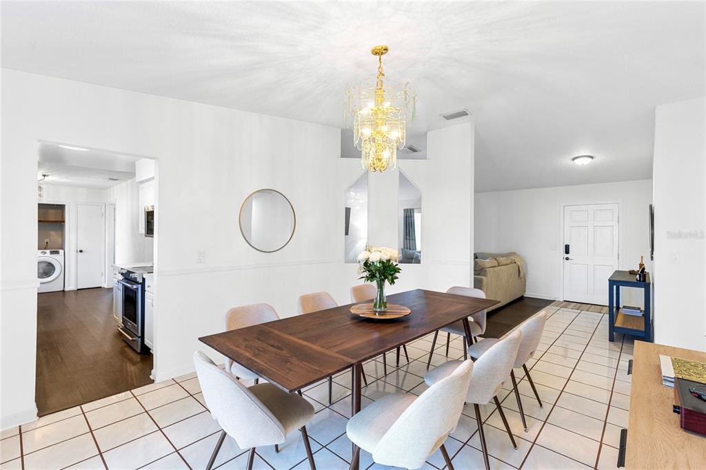 A dining room features a wooden table, six chairs, a crystal chandelier, and tiled floors — 710 BRIARWOOD DRIVE, WINTER SPRINGS, FL