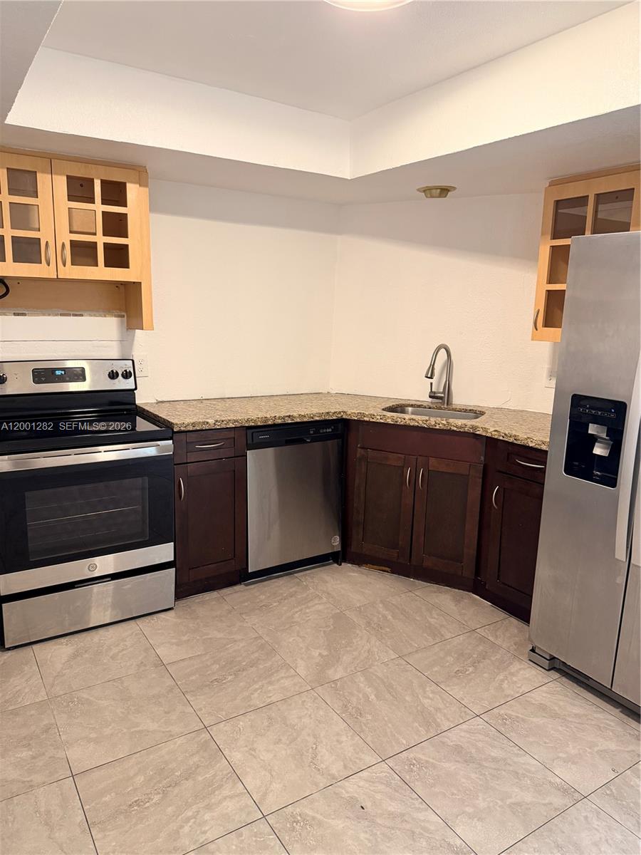 A kitchen features dark wood cabinets, stainless steel appliances, and beige granite countertops — 6613 Evergreen Dr # A, Miramar FL 33023, MIRAMAR, FL