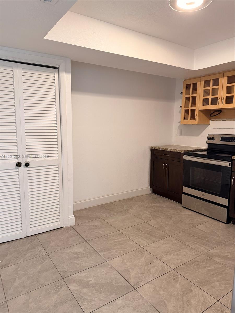 A kitchen features a white louvered closet door, dark cabinets, and a stainless steel stove — 6613 Evergreen Dr # A, Miramar FL 33023, MIRAMAR, FL
