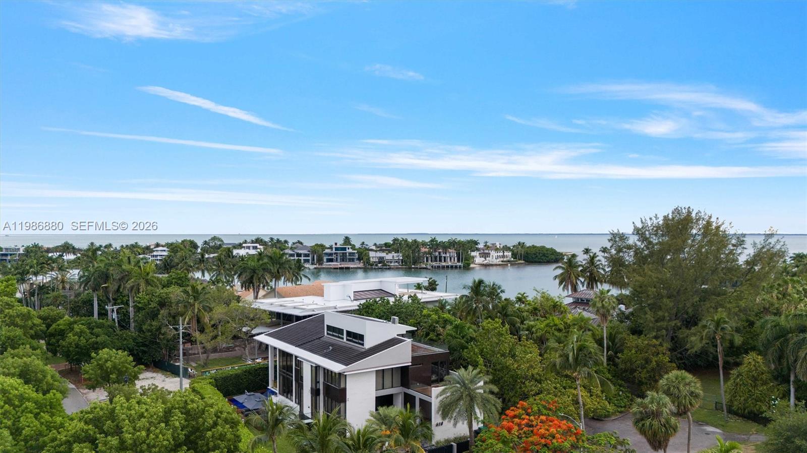 An aerial view shows a modern white house surrounded by lush trees near a bay — 610 Harbor Cir, Key Biscayne FL 33149, KEY BISCAYNE, FL