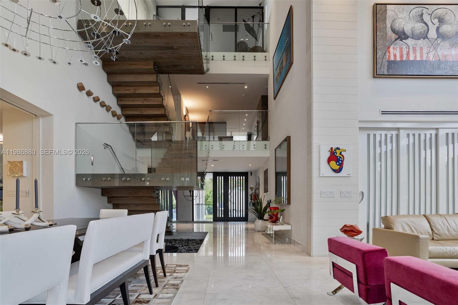 A modern, high-ceilinged living and dining area features a floating wooden staircase with glass railings — 610 Harbor Cir, Key Biscayne FL 33149, KEY BISCAYNE, FL