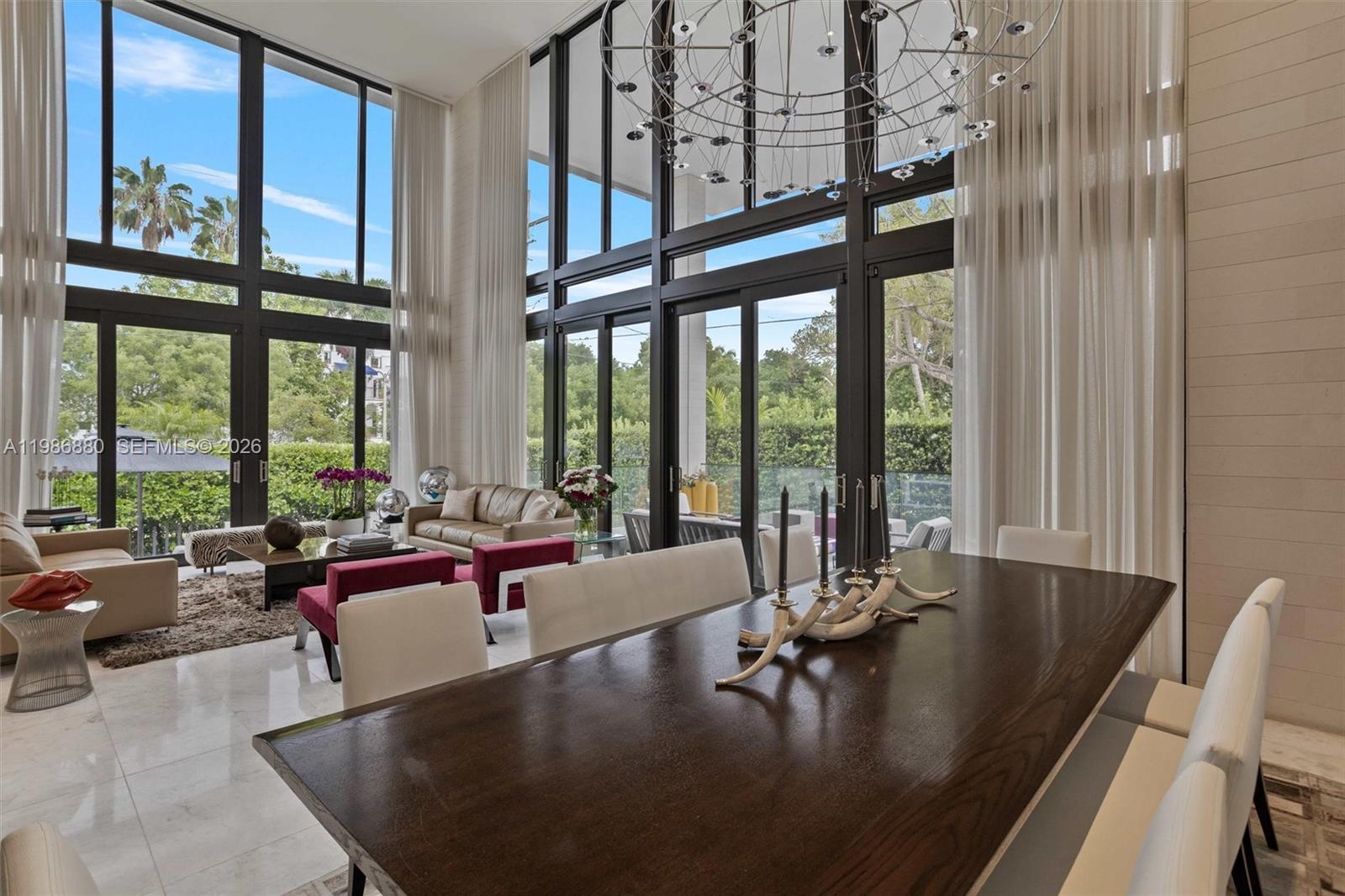 A dining area with a dark wood table overlooks a living room with floor-to-ceiling windows — 610 Harbor Cir, Key Biscayne FL 33149, KEY BISCAYNE, FL