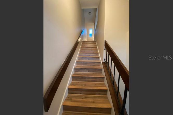 A straight staircase with wood-look treads and a dark wooden handrail leads upward — 3118 S SEMORAN BOULEVARD UNIT N8, ORLANDO, FL