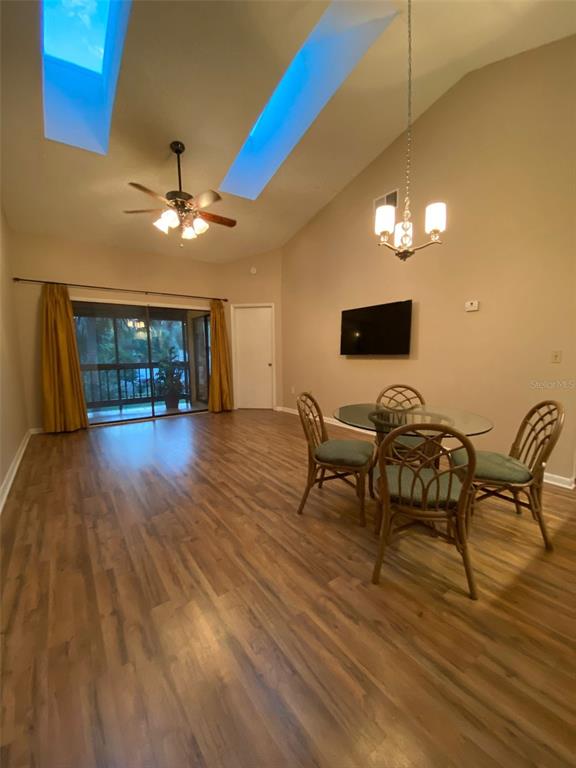 A living and dining area with wood-look flooring, vaulted ceilings, skylights, and a sliding door — 3118 S SEMORAN BOULEVARD UNIT N8, ORLANDO, FL