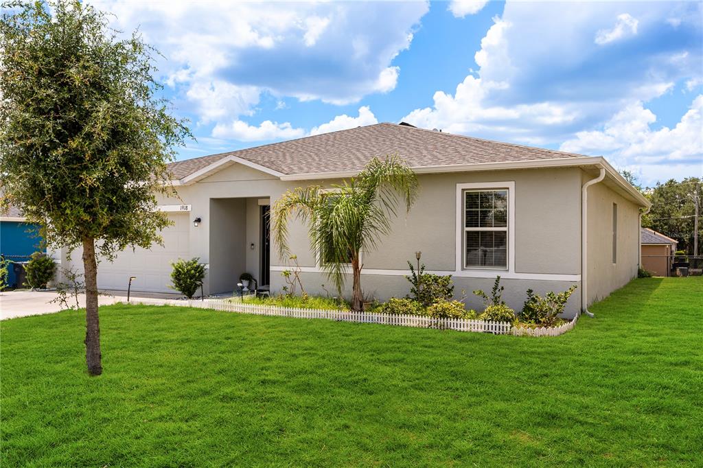 A single-story house with a light-colored exterior, a two-car garage, and a front lawn — 1918 MICHIGAN DRIVE, KISSIMMEE, FL