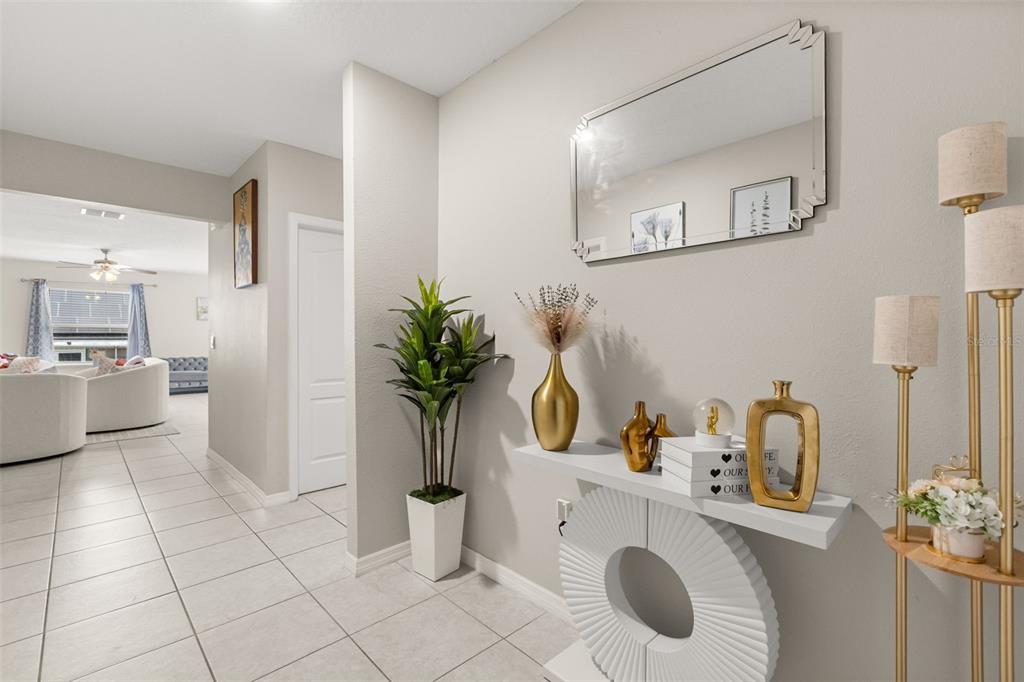 A bright entryway features a white console table, a wall mirror, and tiled flooring — 1918 MICHIGAN DRIVE, KISSIMMEE, FL