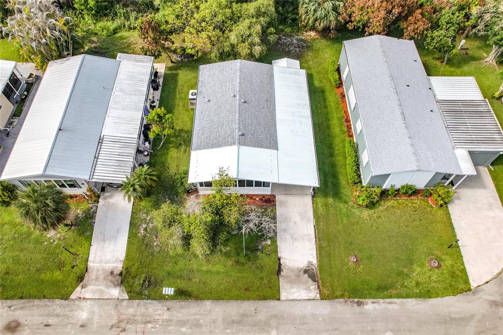 An aerial view shows three manufactured homes with driveways and grassy yards along a street — 8227 CINNAMON LANE, PORT ST LUCIE, FL