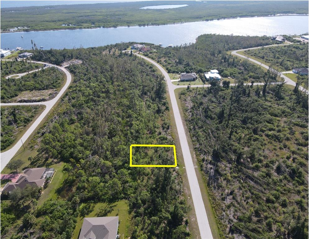 An aerial view shows a vacant, wooded residential lot outlined in yellow along a paved road — 16042 LANKFORD COURT, PORT CHARLOTTE, FL