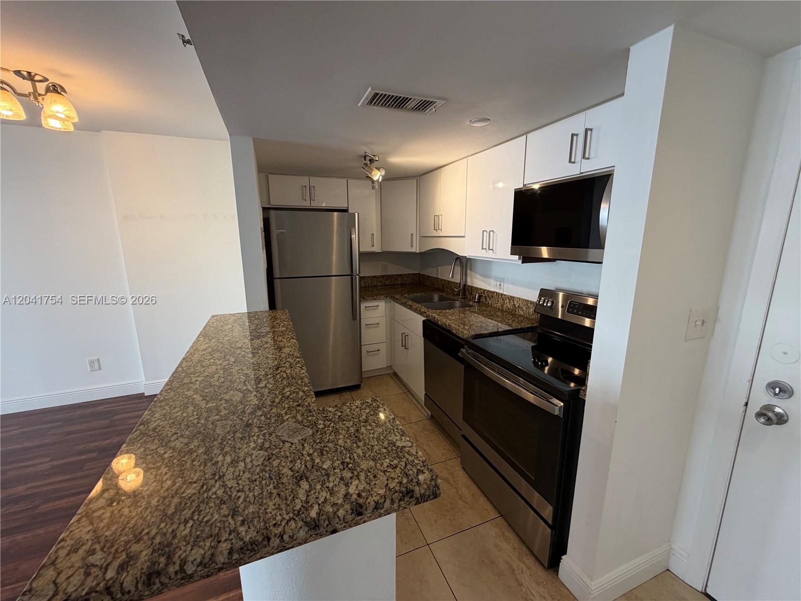 A kitchen features stainless steel appliances, white cabinets, and a granite-topped breakfast bar — 770 Claughton Island Dr # 707, Miami FL 33131, MIAMI, FL