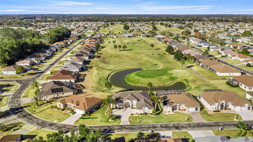 An aerial view shows a suburban neighborhood with houses surrounding a golf course and pond — 5801 NW 18TH STREET, OCALA, FL