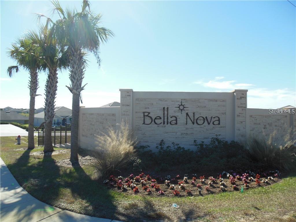A stone monument sign for Bella Nova stands near palm trees and a flower bed — 119 BELLA DRIVE, DAVENPORT, FL