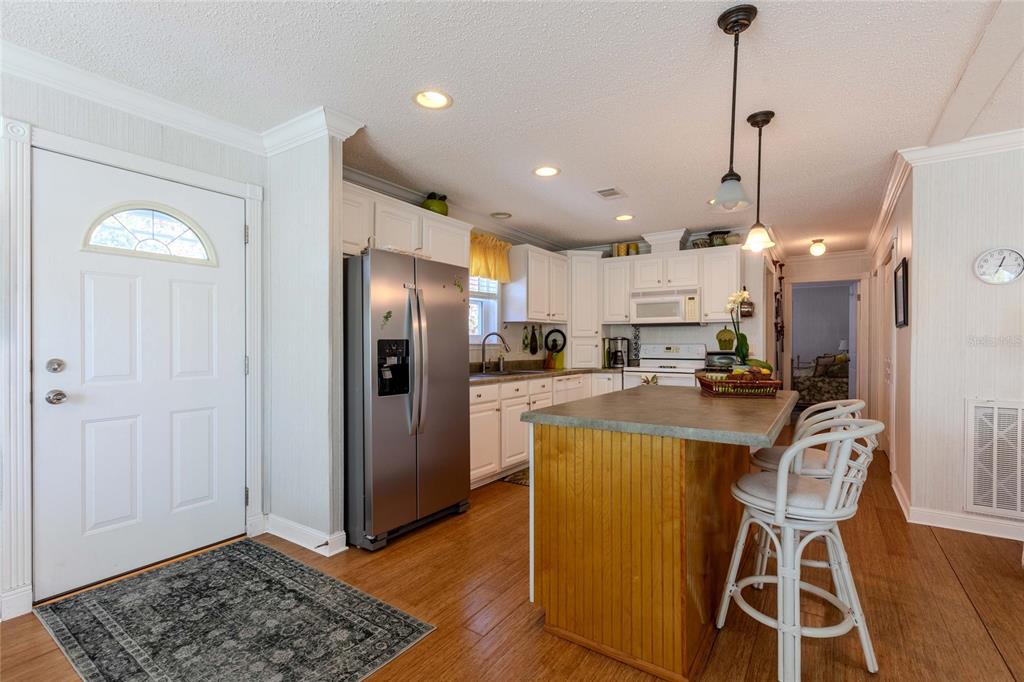 A kitchen with white cabinets, a wooden island, stainless steel appliances, and wood-look flooring — 2100 KINGS HIGHWAY UNIT 52, PORT CHARLOTTE, FL
