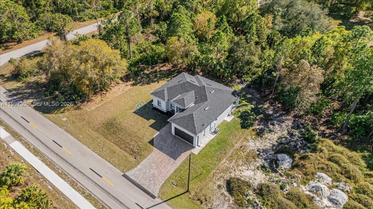 An aerial view shows a single-story house with a dark roof and paved driveway — 1504 E 6th, Lehigh Acres FL 33972, LEHIGH ACRES, FL