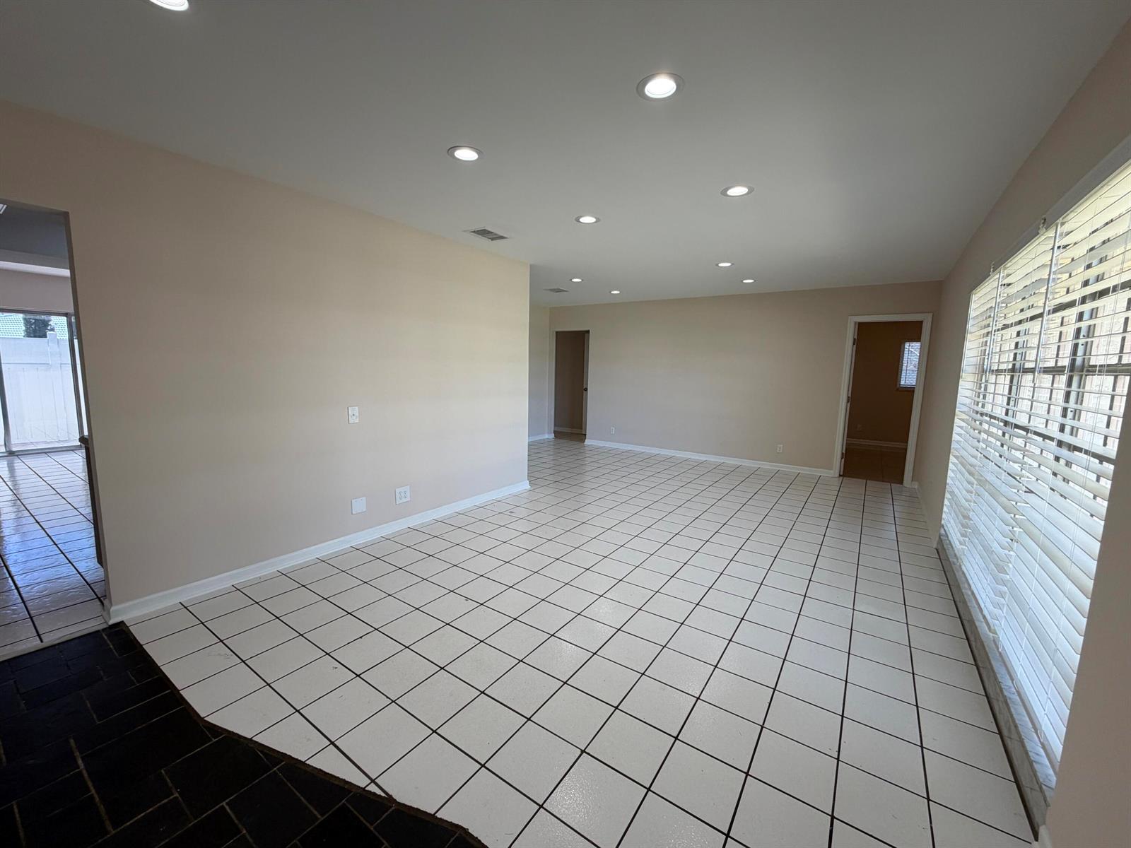 An empty room features white tiled floors, recessed lighting, and beige walls — 499 W Conference Drive, Boca Raton FL 33486, BOCA RATON, FL