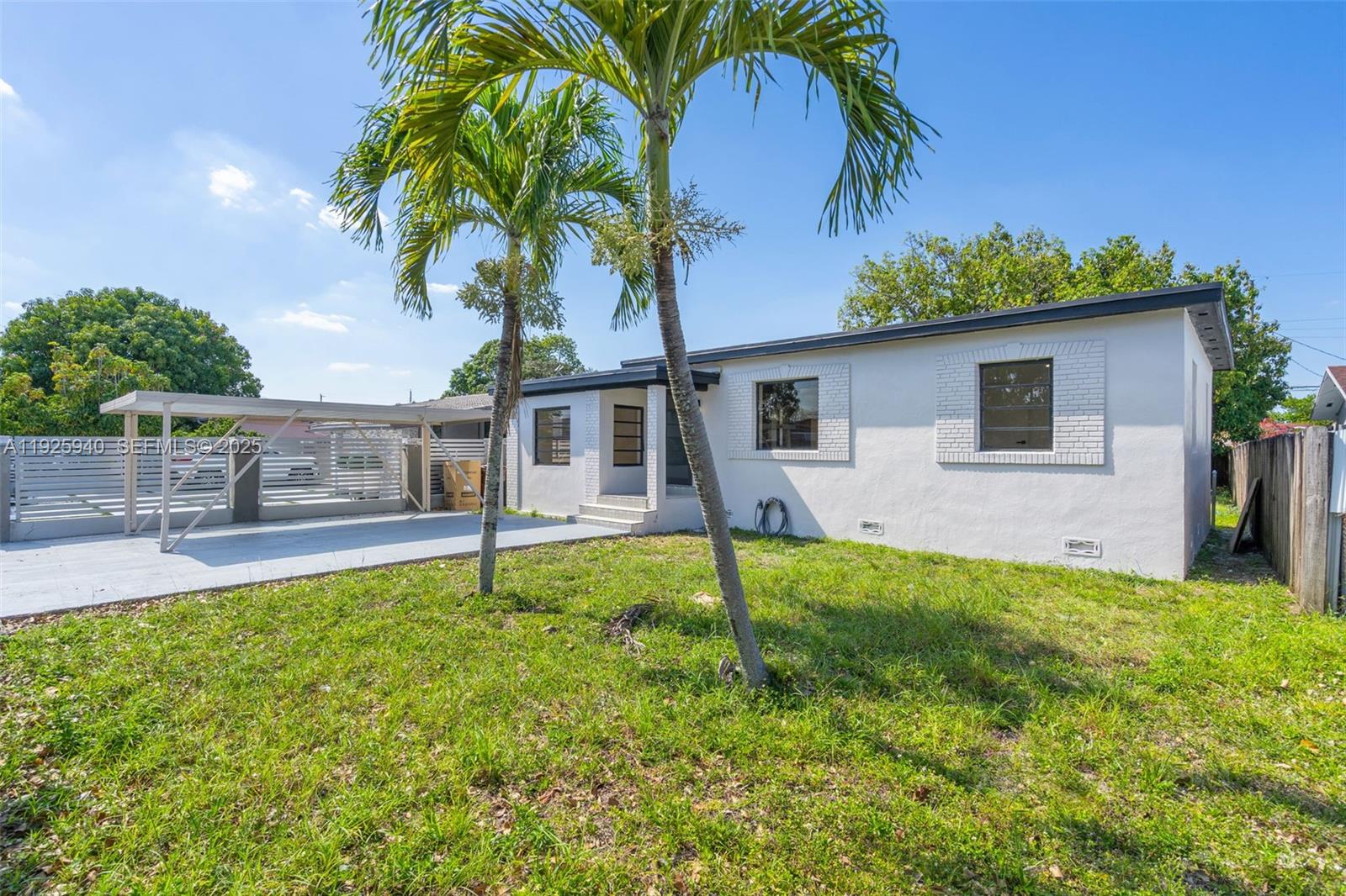 The exterior of a white, single-story house features a carport and two palm trees — 739 W 30th St, Hialeah FL 33012, HIALEAH, FL