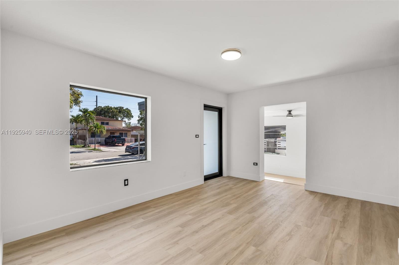 This room features white walls, light wood-look flooring, a large window, and a glass door — 739 W 30th St, Hialeah FL 33012, HIALEAH, FL