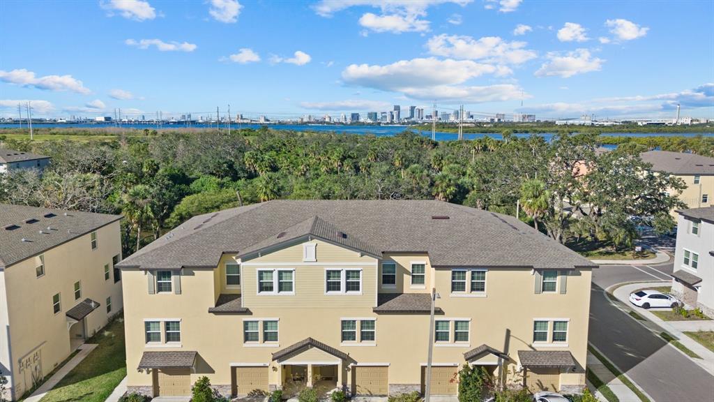 An aerial view shows a multi-story tan townhouse complex with a view of a city skyline — 809 TENNYSON MILL CIRCLE, TAMPA, FL