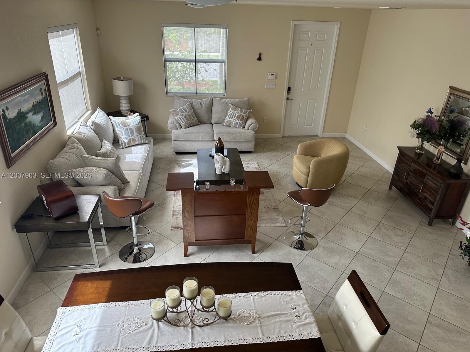 A high-angle view shows a living room with tile floors, a sofa, chairs, and dining area — HOMESTEAD, FL
