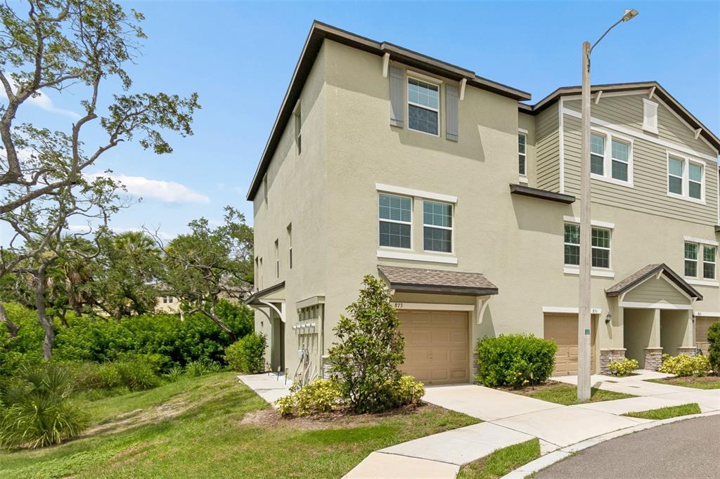 Exterior view of two adjacent townhomes with tan stucco, beige siding, and brown garage doors — 873 TENNYSON MILL CIRCLE, TAMPA, FL