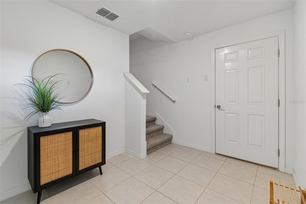 A three-story townhouse with a tan stucco exterior, a single-car garage, and a grassy yard — 873 TENNYSON MILL CIRCLE, TAMPA, FL