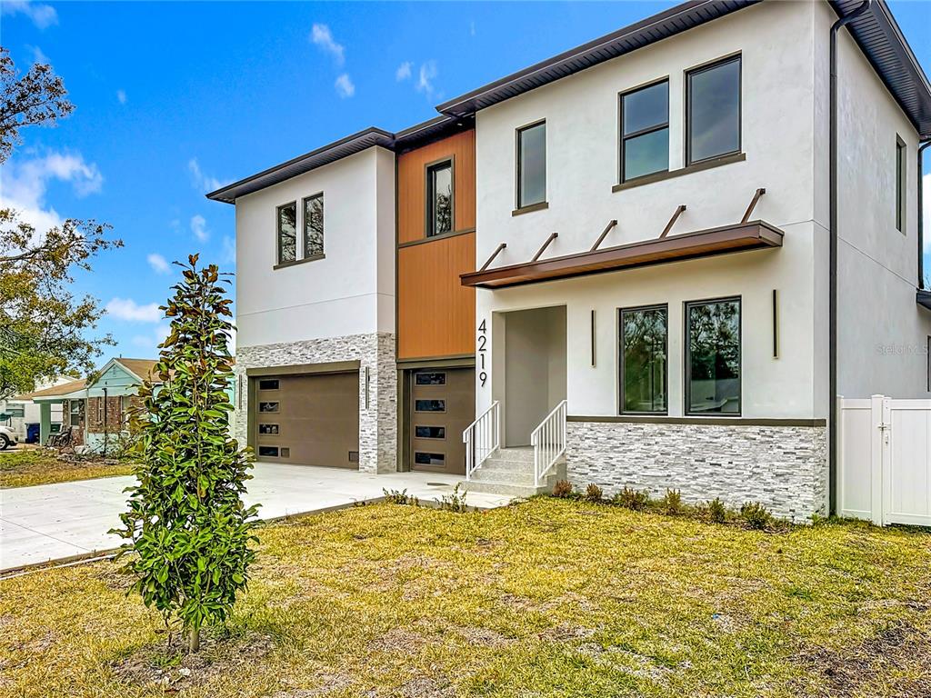 A modern two-story house features a white stucco exterior, stone accents, and a brown garage — 4219 W BAY VIEW AVENUE, TAMPA, FL