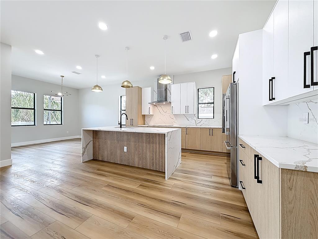 A modern kitchen features a slatted wood island, white cabinetry, and light wood-toned lower cabinets — 4219 W BAY VIEW AVENUE, TAMPA, FL