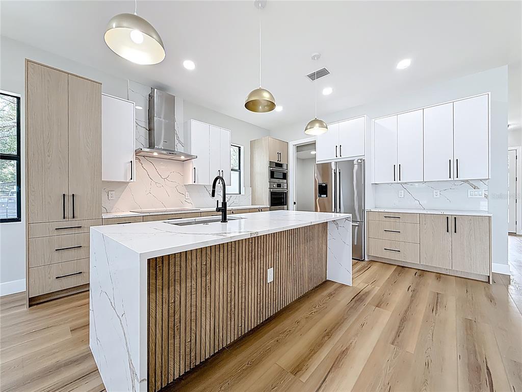 A modern kitchen features a slatted wood island, white marble countertops, and two-toned cabinetry — 4219 W BAY VIEW AVENUE, TAMPA, FL