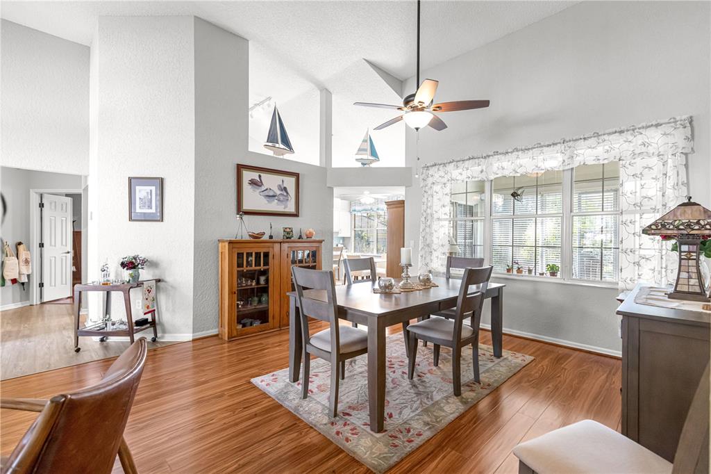 A dining area with a glass-top table, white chairs, and an adjacent kitchen with stainless appliances — 8430 SW 108TH PLACE ROAD, OCALA, FL