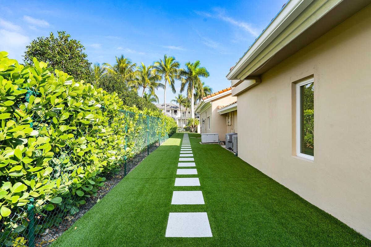 A side yard features a green lawn with a stone path alongside a beige house — 533 E Alexander Palm Road, Boca Raton FL 33432, BOCA RATON, FL