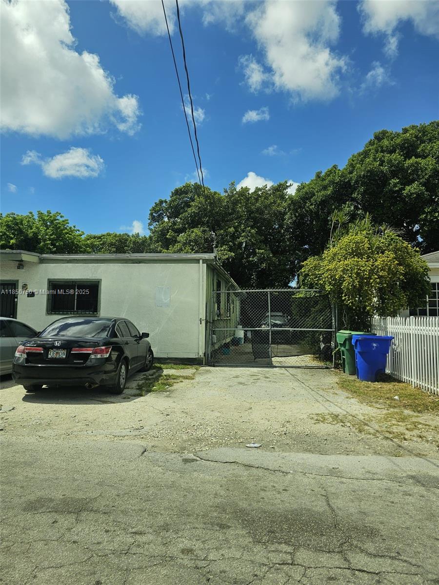 A black sedan is parked on a concrete driveway next to a house with a gate — 140 NE 83rd St, Miami FL 33138, MIAMI, FL