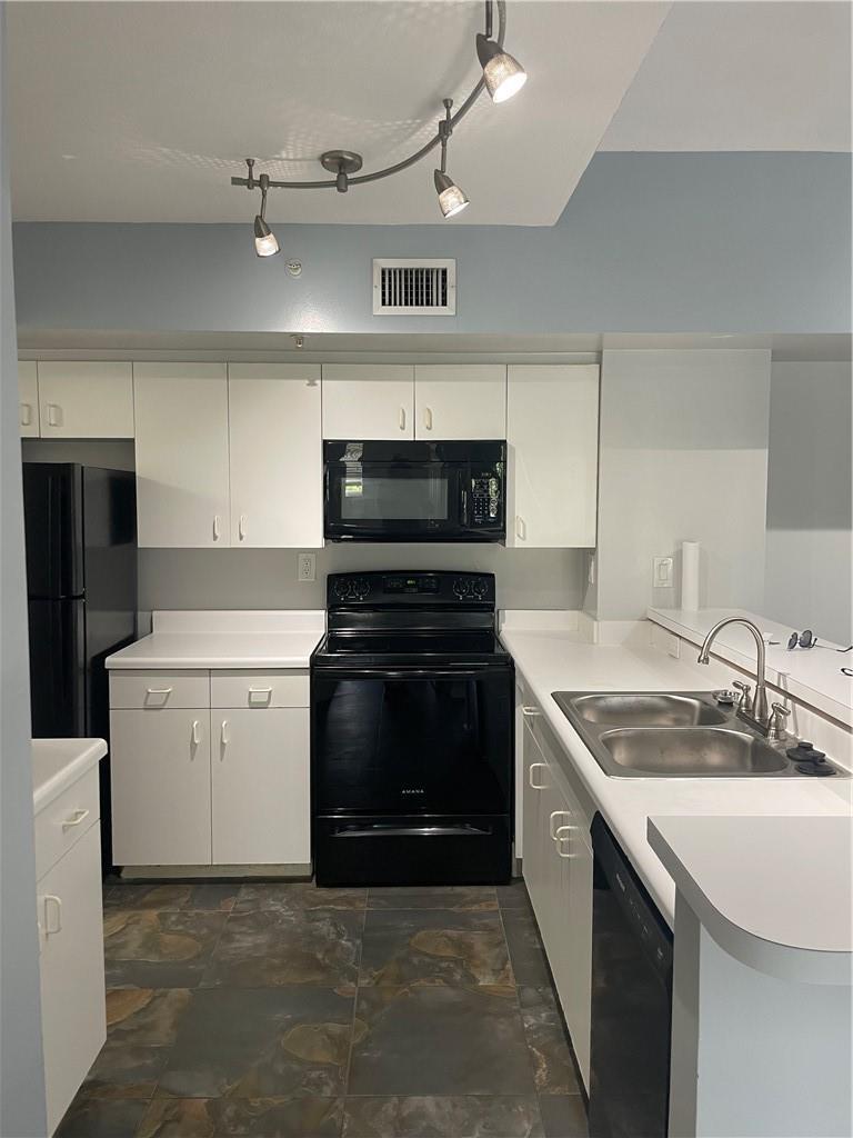 A kitchen features white cabinets, black appliances, a double sink, and dark slate-style flooring — 2640 S University Drive # 319, Davie FL 33328, DAVIE, FL
