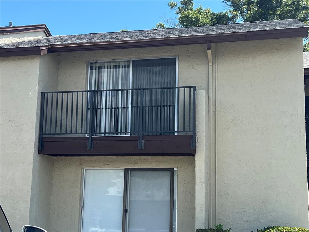 A two-story building exterior features a second-floor balcony with a black metal railing — 4215 E BAY DRIVE UNIT 1702H, CLEARWATER, FL
