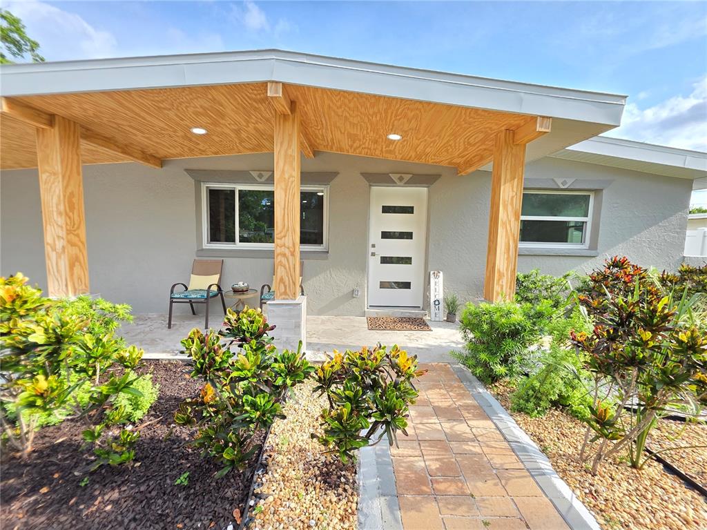 A gray house exterior features a covered porch with wooden posts and a paved walkway — 138 DAVISON AVENUE NE, ST PETERSBURG, FL