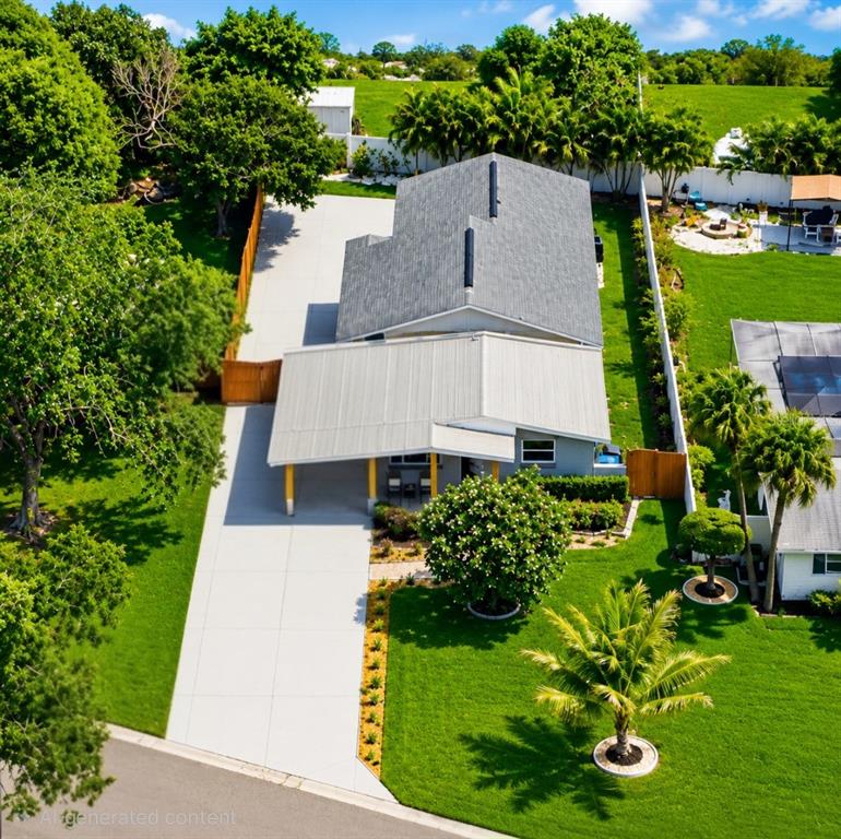 An aerial view of a house with a metal carport, concrete driveway, and large lawn — 138 DAVISON AVENUE NE, ST PETERSBURG, FL