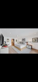 A bedroom features a platform bed, light wood flooring, white walls, and a wall-mounted television — 6110 N Ocean Boulevard # 39, Ocean Ridge FL 33435, OCEAN RIDGE, FL