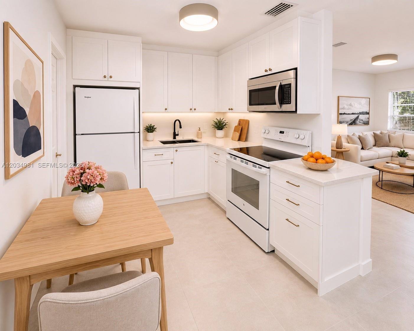 A bright kitchen features white cabinetry, stainless steel appliances, and an adjacent dining area — 545 NE 64th St, Miami FL 33138, MIAMI, FL