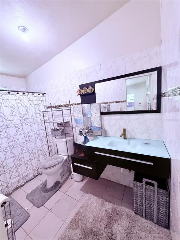 A bathroom features a floating vanity with a glass top, a toilet, and tiled walls — KM 5.0 906, YABUCOA, PR