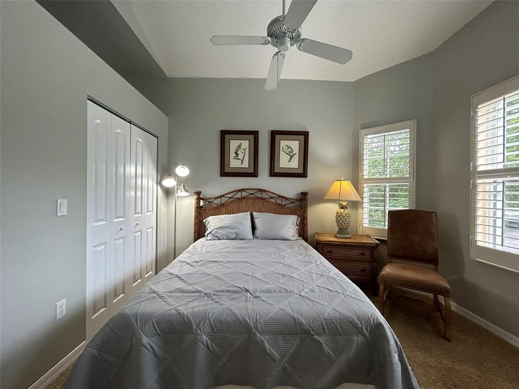 A bedroom features a bed with a rattan headboard, a ceiling fan, and two windows — 3706 54TH DRIVE W UNIT 204, BRADENTON, FL