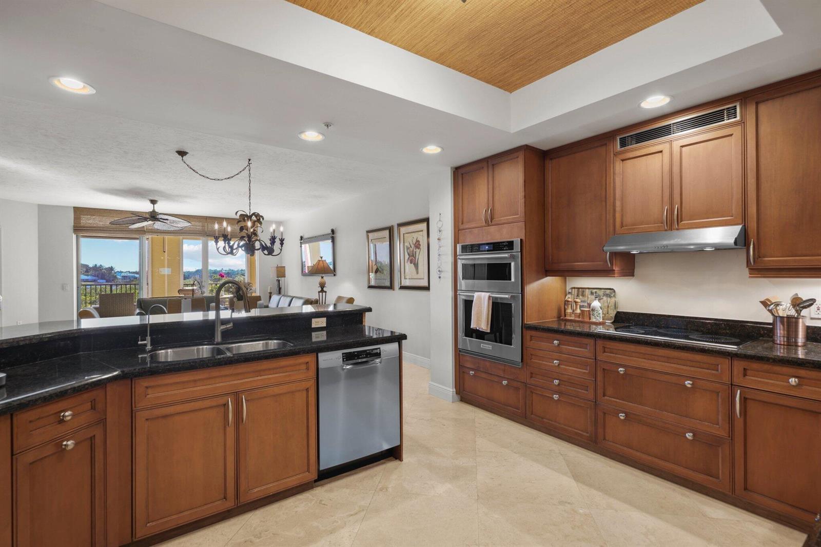 A kitchen with wood cabinets, dark countertops, and stainless steel appliances opens to a living area — 500 S Us Highway 1 # 202, Jupiter FL 33477, JUPITER, FL