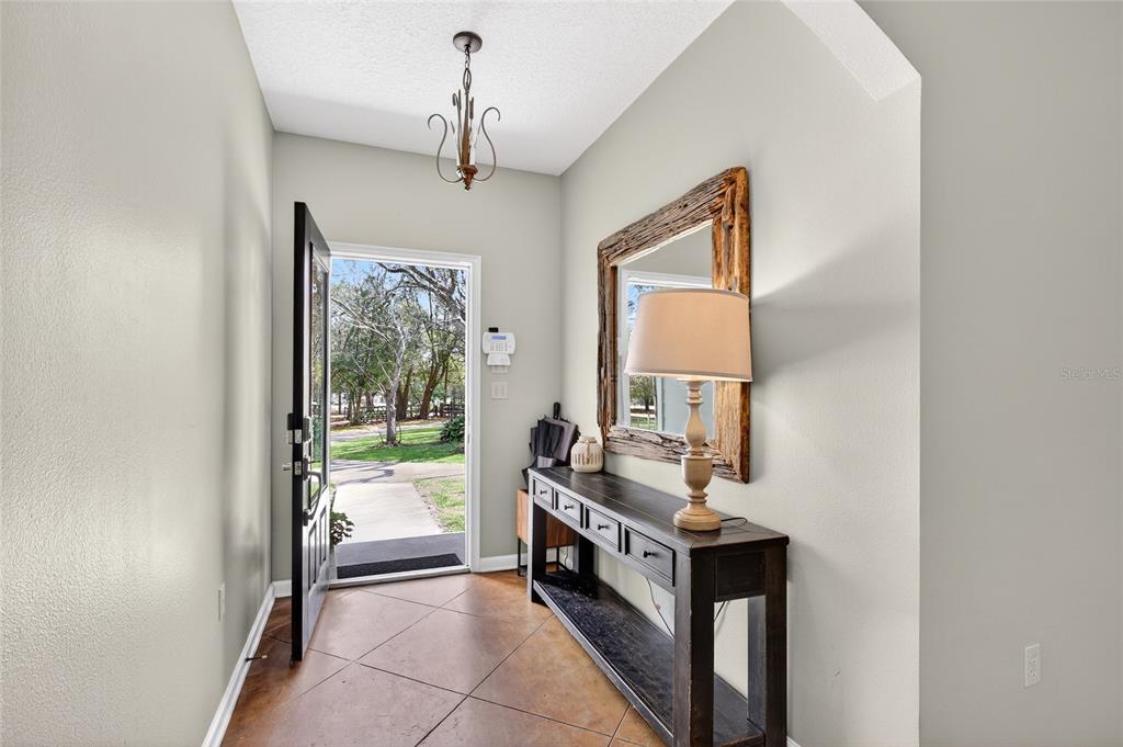 An entryway features tile flooring, a console table with a lamp, and an open door — 22301 CORONADO SOMERSET DRIVE, SORRENTO, FL