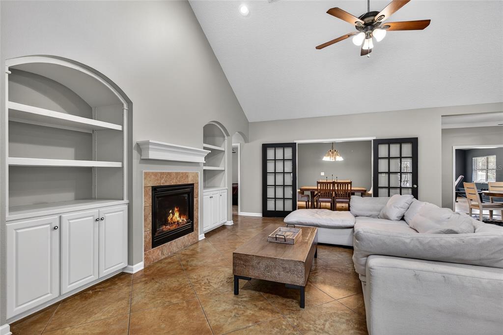 A living room with a fireplace, built-in shelving, tile flooring, and a sectional sofa — 22301 CORONADO SOMERSET DRIVE, SORRENTO, FL