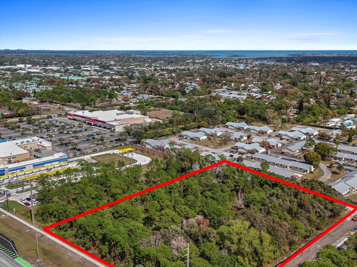 An aerial view shows a rectangular, wooded vacant lot outlined in red near a shopping center — 0 SE Federal Highway, Stuart FL 34994, STUART, FL