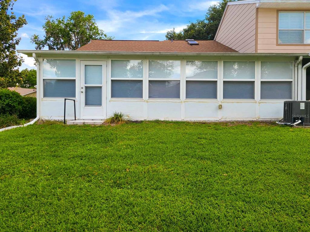 The exterior of a house features a white sunroom with multiple windows and a door — 2321 SE 19TH CIRCLE, OCALA, FL